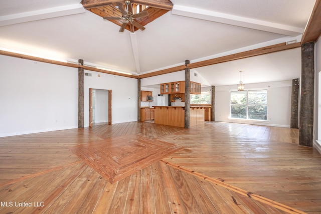 unfurnished living room featuring lofted ceiling with beams, a barn door, ceiling fan, and light hardwood / wood-style flooring