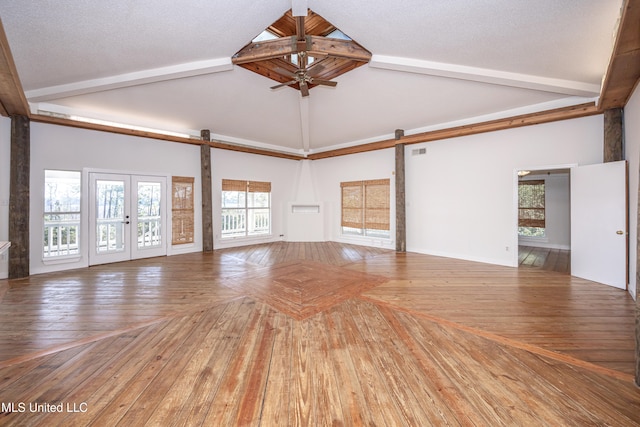 unfurnished living room featuring hardwood / wood-style flooring, a barn door, a textured ceiling, and high vaulted ceiling