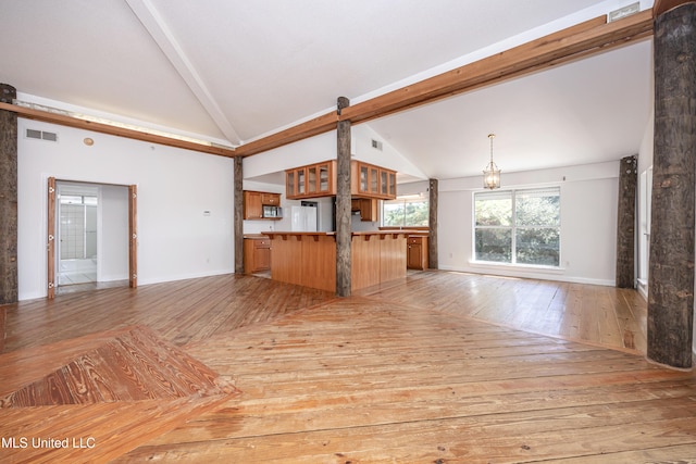 unfurnished living room featuring vaulted ceiling with beams, light hardwood / wood-style flooring, and a barn door