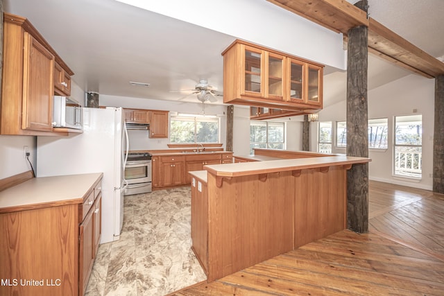 kitchen with vaulted ceiling with beams, stainless steel range oven, kitchen peninsula, light hardwood / wood-style floors, and a breakfast bar area