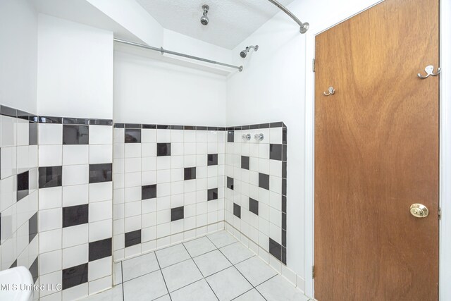 bathroom with a shower, a textured ceiling, and tile patterned floors