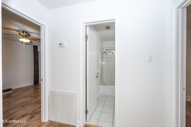 hall with light hardwood / wood-style floors and a textured ceiling