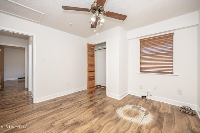 unfurnished bedroom featuring hardwood / wood-style flooring, ceiling fan, a textured ceiling, and a closet