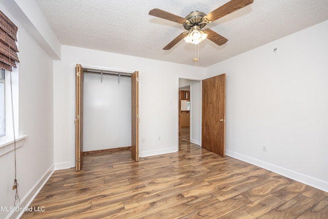 unfurnished bedroom with hardwood / wood-style flooring, ceiling fan, a textured ceiling, and a closet