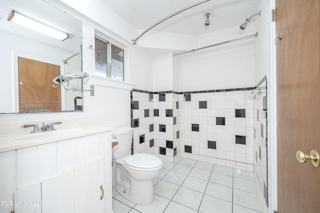 bathroom featuring vanity, tile patterned flooring, toilet, a textured ceiling, and tile walls