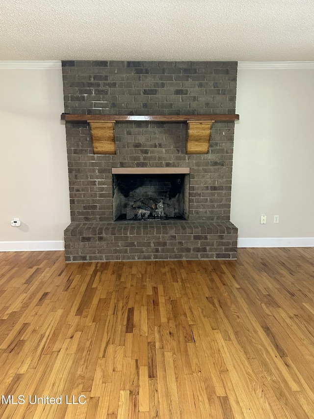 19728 Hwy 63, Moss Point, MS 39562 - detailed view of wood finished floors, a textured ceiling, a brick fireplace, crown molding, and baseboards