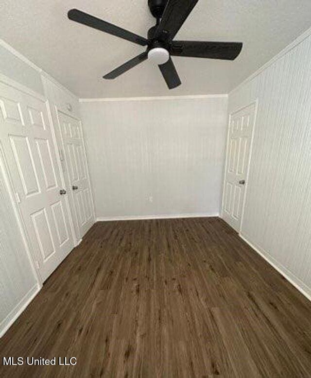 unfurnished bedroom with ceiling fan, dark wood-style flooring, and crown molding