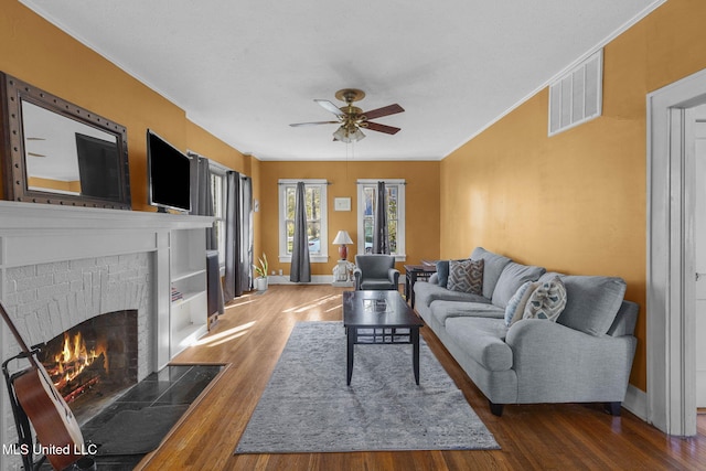 living room featuring ceiling fan, dark wood-type flooring, and a brick fireplace