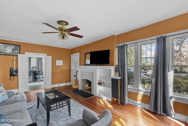 living room featuring wood-type flooring, a brick fireplace, and ceiling fan