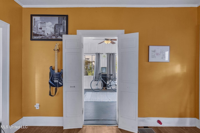 corridor with ornamental molding and hardwood / wood-style flooring