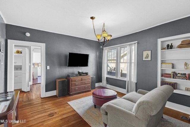 living room featuring hardwood / wood-style flooring, a notable chandelier, and built in features