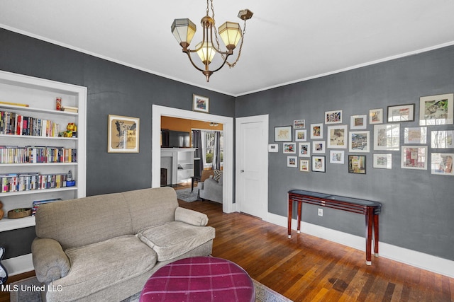 living room featuring built in features, ornamental molding, dark hardwood / wood-style floors, and a notable chandelier