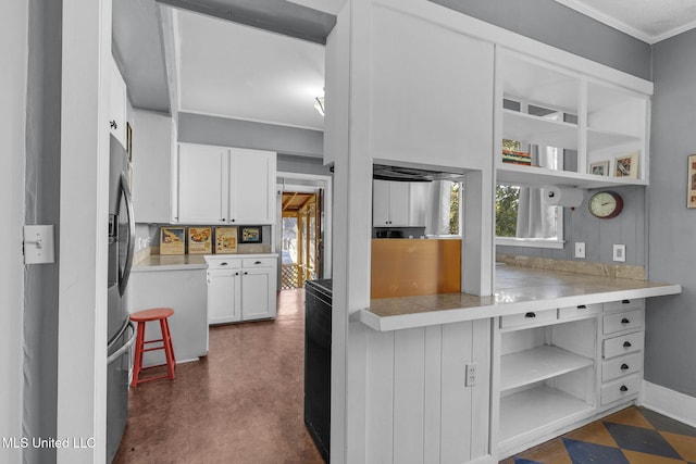 kitchen with stainless steel fridge, white cabinetry, and ornamental molding