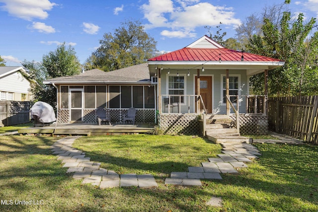 view of front of house with a sunroom, a wooden deck, and a front lawn