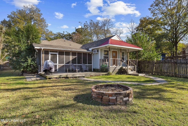 back of house featuring a sunroom, a yard, an outdoor fire pit, and a wooden deck