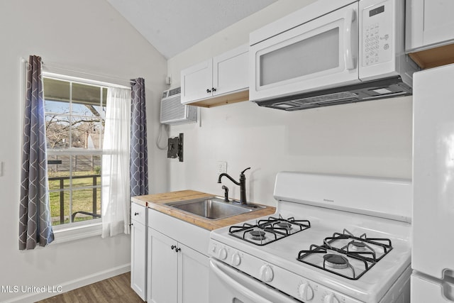 kitchen featuring white cabinetry, sink, a wall unit AC, vaulted ceiling, and white appliances