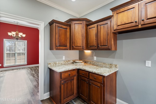 kitchen featuring light stone countertops, hanging light fixtures, ornamental molding, dark wood-type flooring, and an inviting chandelier