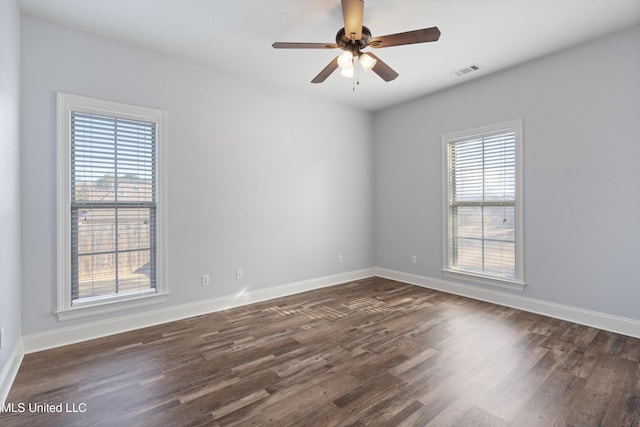 empty room with ceiling fan, dark wood-type flooring, and a healthy amount of sunlight