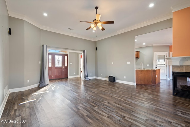 unfurnished living room with sink, ornamental molding, dark hardwood / wood-style floors, and a fireplace