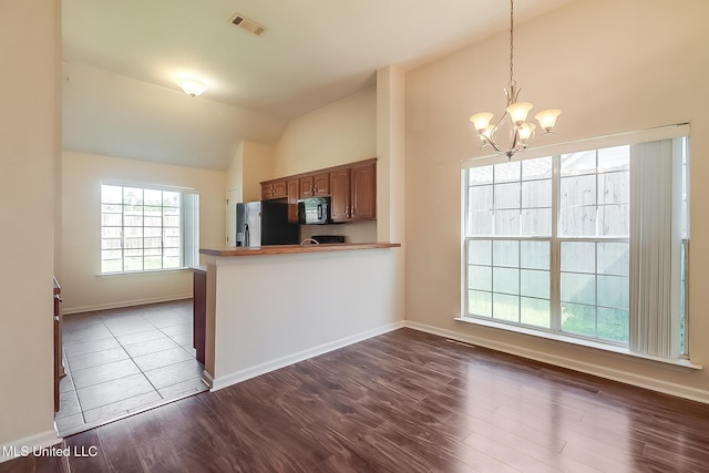 kitchen with lofted ceiling, black appliances, dark wood finished floors, and a notable chandelier