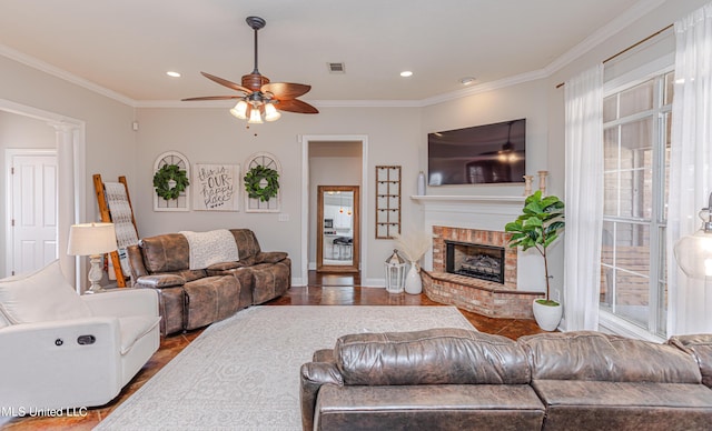 living room with a brick fireplace, crown molding, and hardwood / wood-style floors