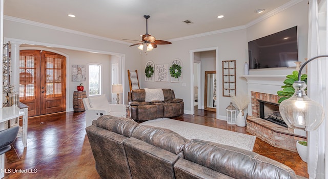 living room with french doors, ceiling fan, ornamental molding, and a fireplace