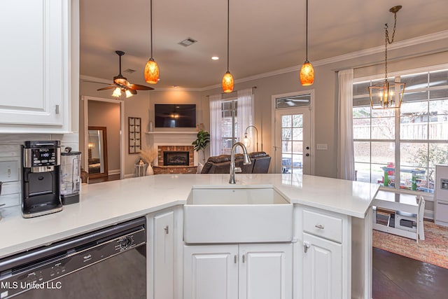 kitchen with sink, dishwasher, a fireplace, ornamental molding, and white cabinets