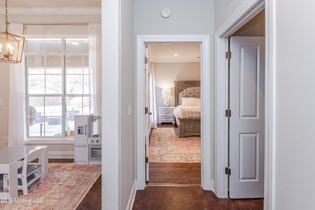 hallway with crown molding and an inviting chandelier