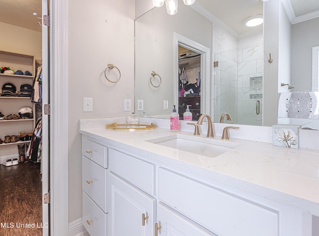 bathroom featuring vanity, hardwood / wood-style floors, crown molding, and a shower with shower door