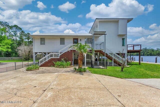 6085 Shawnee St, Kiln, MS 39556 - view of front of property featuring stairway, concrete driveway, metal roof, and a deck with water view