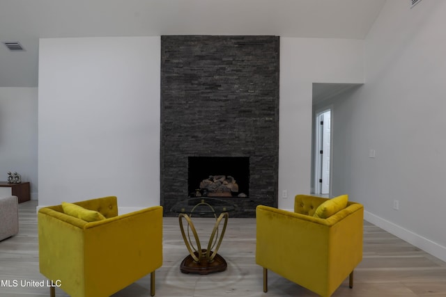 living room with light wood-type flooring, baseboards, a fireplace, and visible vents