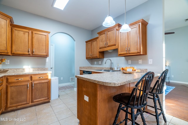 kitchen with a breakfast bar area, sink, decorative light fixtures, and light wood-type flooring