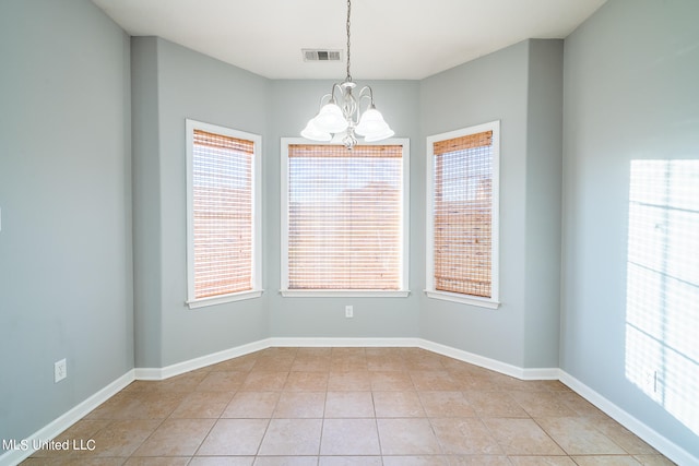 tiled spare room featuring a notable chandelier