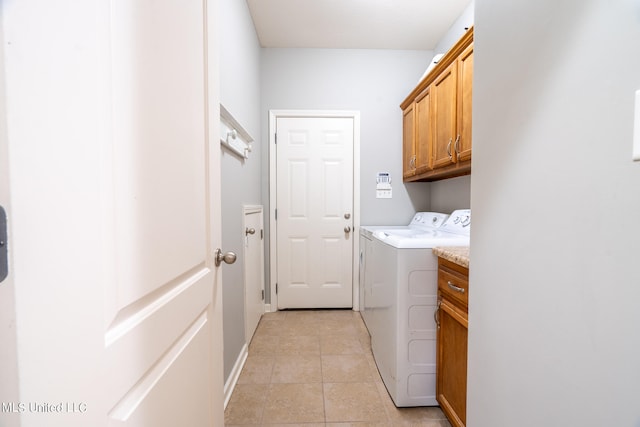 washroom featuring light tile patterned floors, washing machine and dryer, and cabinets