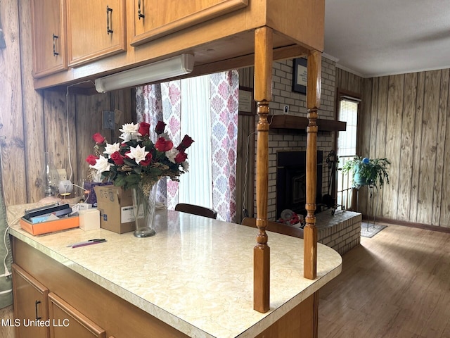 25 Cloverdale Rd, Natchez, MS 39120 - kitchen with wooden walls, light countertops, wood finished floors, brown cabinetry, and a brick fireplace