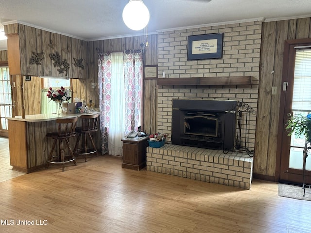 25 Cloverdale Rd, Natchez, MS 39120 - living room featuring crown molding, light wood-style floors, wooden walls, a brick fireplace, and a dry bar
