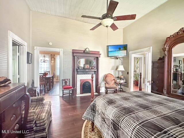 bedroom with a brick fireplace, ceiling fan, a high ceiling, and dark hardwood / wood-style flooring