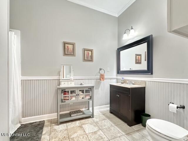 bathroom featuring toilet, ornamental molding, a towering ceiling, vanity, and tile patterned floors