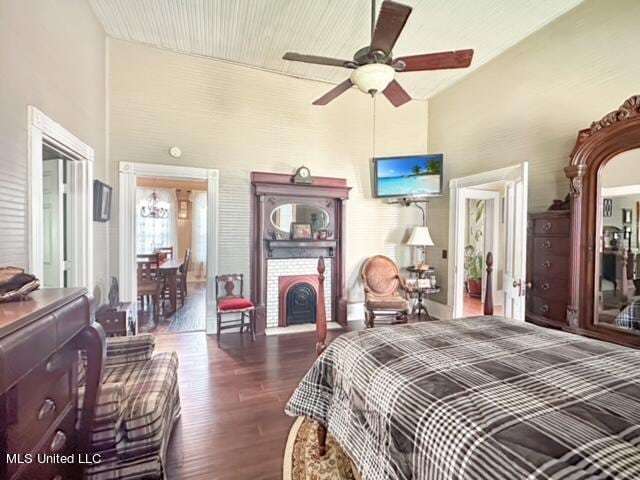 bedroom with a towering ceiling, ceiling fan, a fireplace, and dark hardwood / wood-style flooring