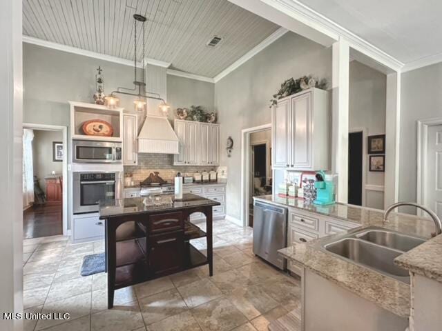 kitchen with custom range hood, stainless steel appliances, backsplash, sink, and decorative light fixtures