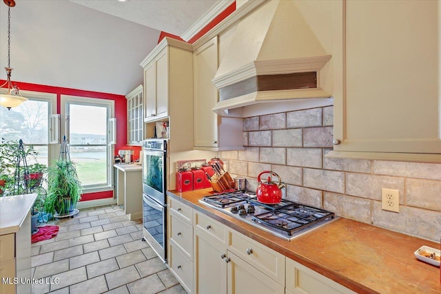 kitchen with custom exhaust hood, hanging light fixtures, light countertops, appliances with stainless steel finishes, and tasteful backsplash