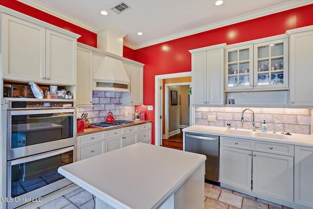 kitchen with visible vents, a sink, light countertops, custom range hood, and appliances with stainless steel finishes