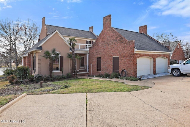 view of front of house featuring a front yard, a balcony, concrete driveway, a garage, and brick siding