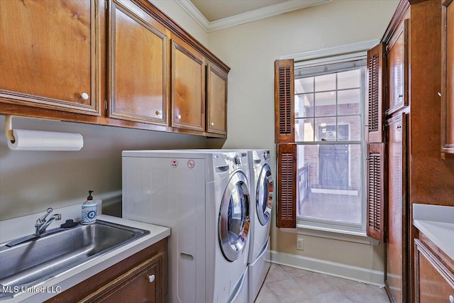 clothes washing area with a sink, crown molding, light tile patterned floors, cabinet space, and separate washer and dryer