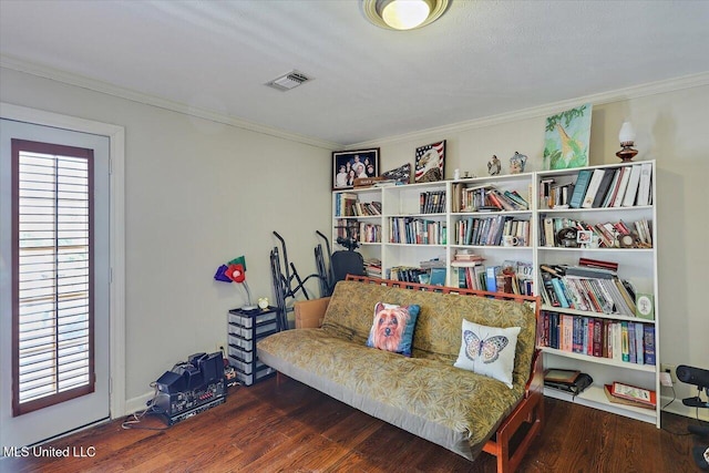 living area with visible vents, ornamental molding, and wood finished floors