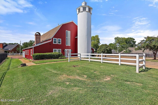 view of home's exterior with fence, a yard, a chimney, an outdoor structure, and a barn