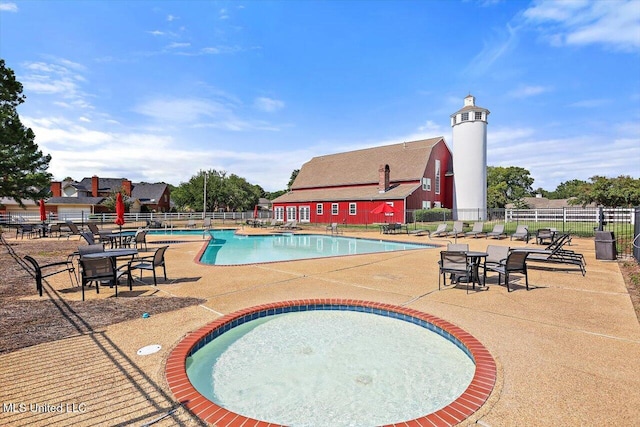 community pool with a patio area, an outdoor structure, and fence