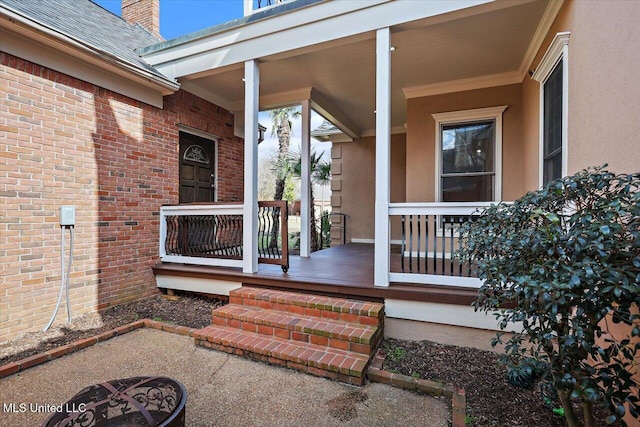 entrance to property featuring a porch, brick siding, and a shingled roof