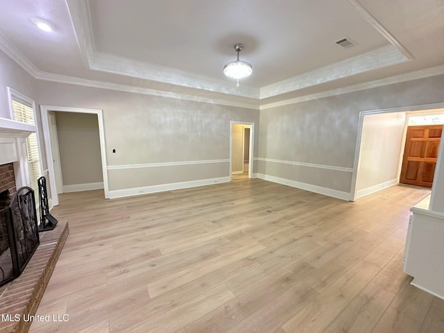 unfurnished living room featuring a raised ceiling, light wood-type flooring, a fireplace, and visible vents