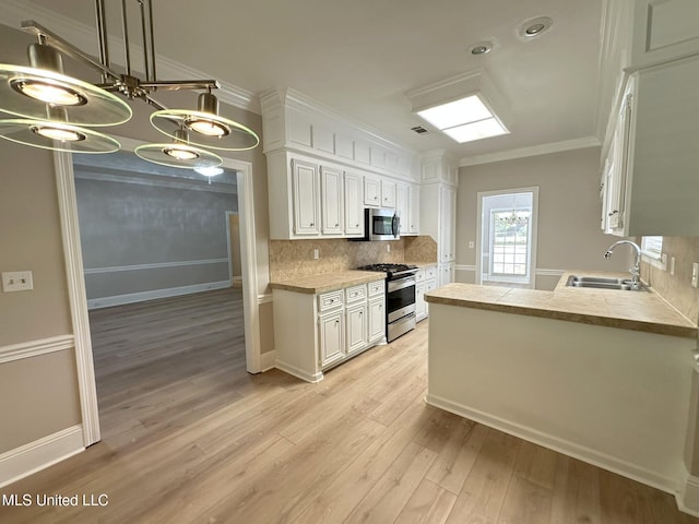 kitchen featuring light wood-style flooring, tasteful backsplash, white cabinets, appliances with stainless steel finishes, and a sink